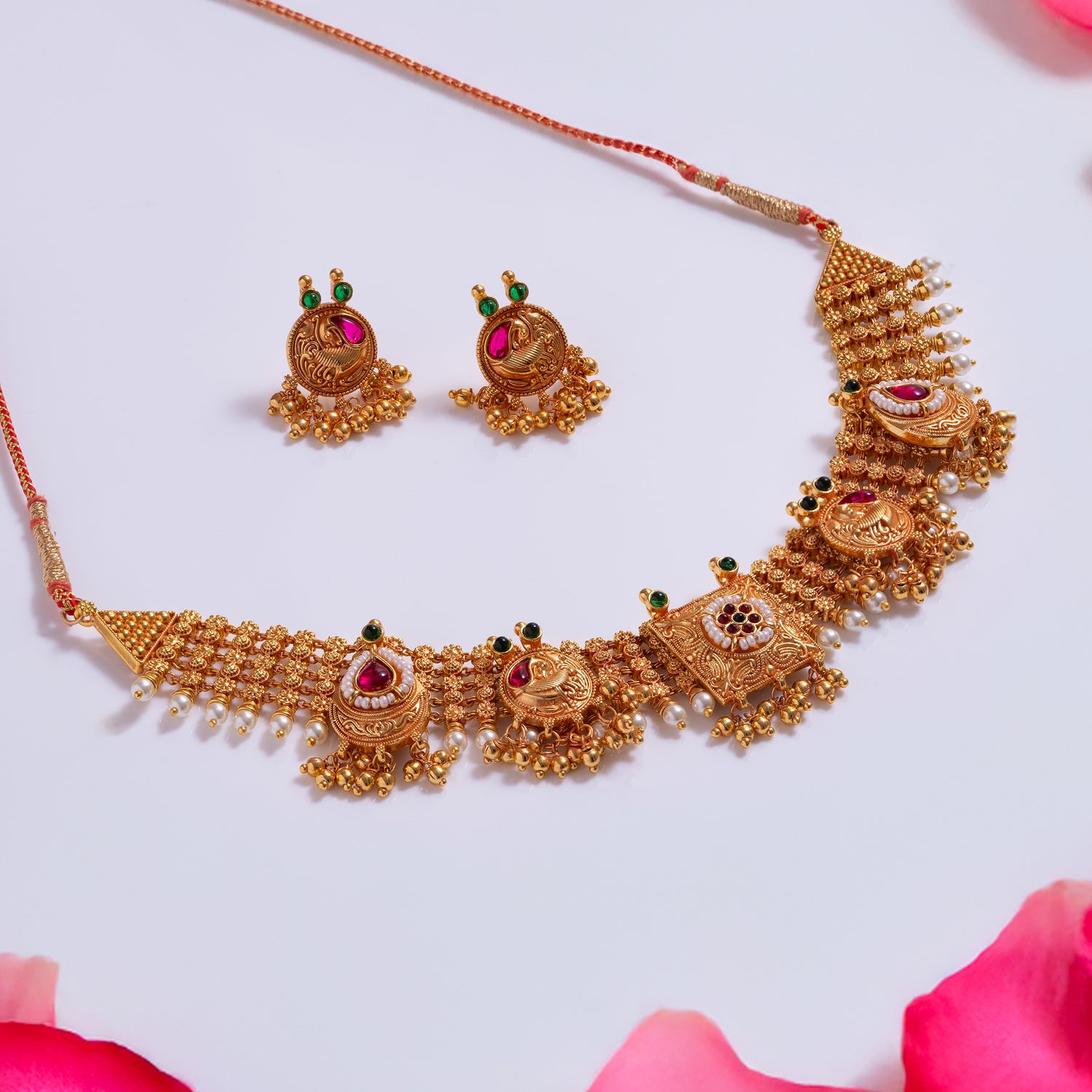 Gold necklace and earrings set on a white background